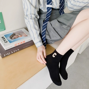 Detail of black cotton ankle sock featuring a white embroidered letter C on the side