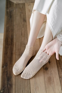 Close-up of beige lace socks with elegant rose floral embroidery and mesh texture