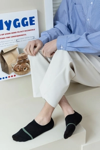Detail of men's black low-cut invisible cotton socks featuring green stripe accents