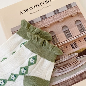 Detail of cotton socks with green ruffled cuffs and vintage floral argyle pattern