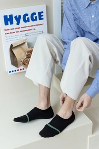 Detail of men's black low cut invisible socks with a green stripe on a light background