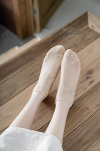Detailed close-up of beige lace mesh boat socks with elegant rose floral embroidery
