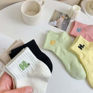Detail view of cotton ankle socks with H letter embroidery in various pastel colors