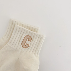 Close-up of cream cotton low cut sock with brown embroidered C letter detail
