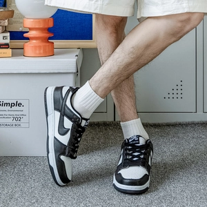 Classic low-top black and white leather skate shoes worn in a minimalist home setting