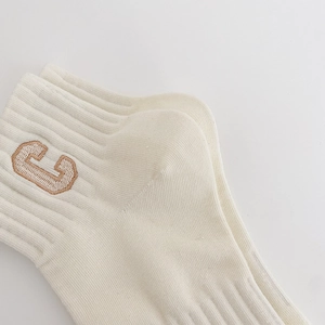 Detailed close-up of ribbed combed cotton ankle socks with letter C embroidery design