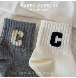 Detail of ribbed knit cotton socks in grey and cream with jacquard letter C design