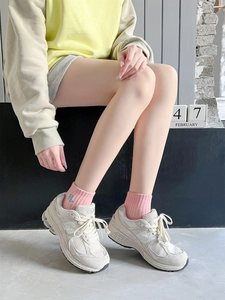 Detail of pink ribbed mid-calf socks with H letter embroidery and vintage sneakers