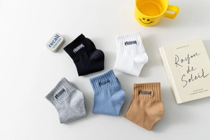 Détail de chaussettes en coton colorées avec broderie Freedom sur fond blanc