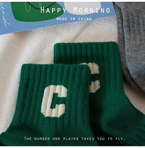 Close-up of dark green ribbed cotton socks with white letter C jacquard detail