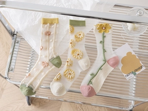 Detail of sheer glass silk socks with floral embroidery on a modern glass trolley
