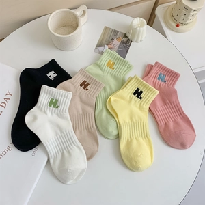 Close-up of cotton knit socks featuring vertical stripes and letter H embroidery detail