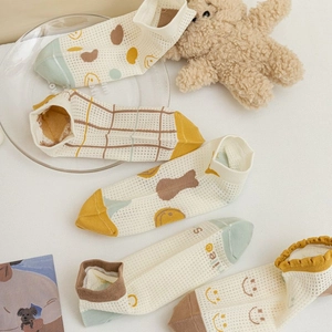 Close-up of low-cut mesh socks in yellow and beige with cute cartoon patterns