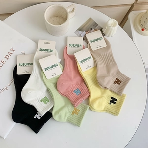 Detail view of six candy-colored sports socks with H embroidery and paper card packaging