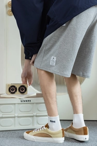 Gros plan sur un short en coton gris avec chaussettes blanches et baskets en daim