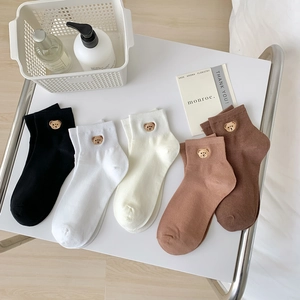Detail view of five pairs of cotton socks with cute brown bear embroidery in earth tones