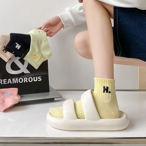 Detailed embroidery of letter H on premium cotton socks in various pastel colors