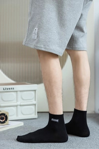 Détail de chaussettes en coton noir avec broderie Freedom et short en maille