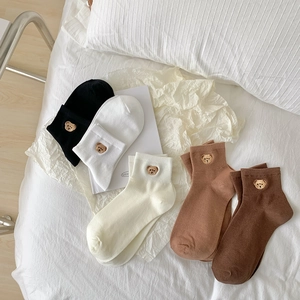 Detail view of five pairs of cotton socks featuring cute bear embroidery in neutral colors