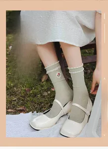 Detail of light green mid-calf cotton socks with floral embroidery and ruffle trim