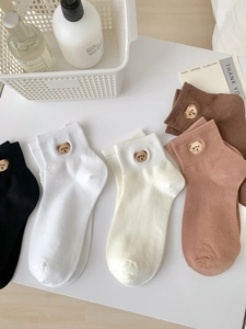 Close-up of bear embroidery and ribbed cuffs on cotton socks in multiple neutral colors