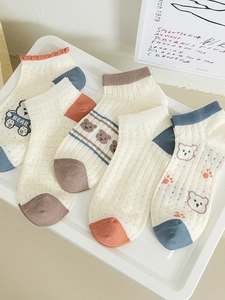 Detail view of five pairs of cartoon bear ankle socks in cream and neutral tones