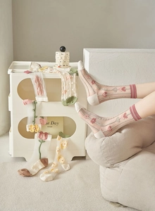 Detail view of sheer mesh socks with delicate tulip and floral embroidery patterns