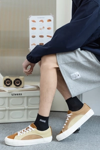 Détail de chaussettes noires brodées Freedom avec short gris et chaussures en toile vintage