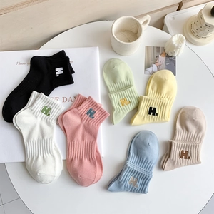 Close-up of seven pairs of assorted pastel cotton socks featuring embroidered H letters