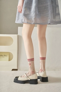 Detail of sheer glass silk socks featuring pink heart embroidery and striped cuffs