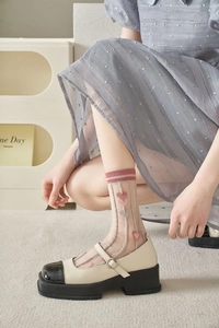 Detail of sheer tulip mesh socks with pink heart embroidery and platform Mary Jane shoes