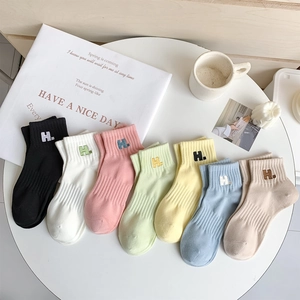 Detail of seven macaron-colored cotton socks with H embroidery on a white table