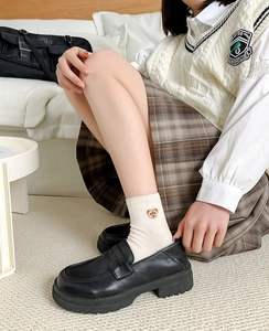 Detailed shot of cream crew socks with bear embroidery paired with black loafers