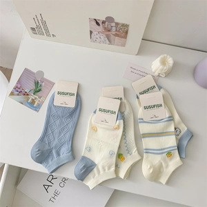 Close-up of blue and cream cotton ankle socks with bear embroidery and floral patterns