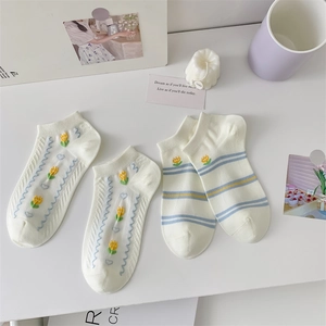 Close-up of two pairs of white cotton socks with tulip embroidery and blue striped details