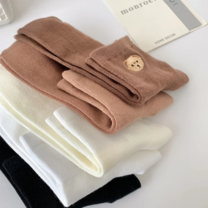 Macro detail of cotton socks featuring ribbed texture and cute bear embroidery accents