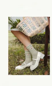 Detail of light green mid-calf socks with floral embroidery and delicate lace edges