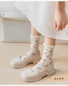 Close-up of white ruffled socks with pink floral pattern worn with beige Mary Jane shoes
