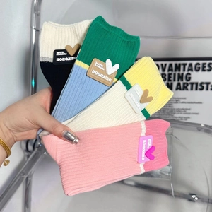 Detail of four pairs of ribbed cotton socks with heart charms and rubber branding logos