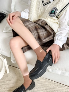 Close-up of black platform loafers paired with brown bear embroidery crew socks