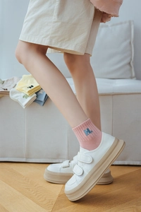 Close-up of pastel cotton socks with ribbed cuffs and H. letter embroidery detail
