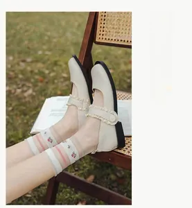 Detail of floral sheer crew socks paired with lace Mary Jane shoes on green grass
