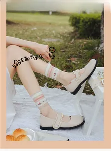 Detail of white mesh mid-calf socks with floral embroidery and Mary Jane buckle shoes