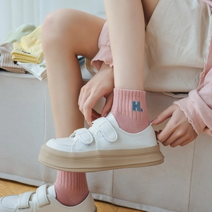 Detailed view of white cotton socks with blue embroidered letter H on ribbed ankle cuff
