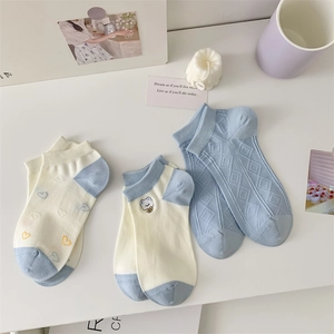 Detail of blue cotton socks with bear embroidery, heart patterns and argyle knit textures