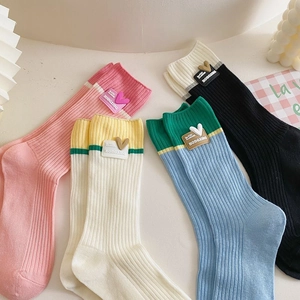 Detail of colorful cotton crew socks with heart-shaped brand labels in a cozy Ins style layout