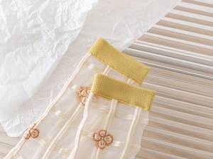 Close-up of sheer tulip socks with yellow ribbed cuffs and delicate mesh textures