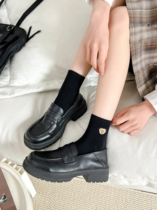 Detail of embroidered bear icon on black mid-calf socks with platform loafers