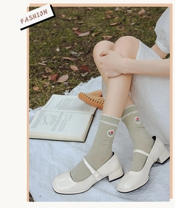 Detail of light green mid-calf socks with ruffle trim and tiny red floral embroidery