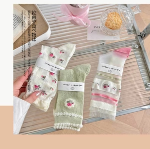 Three pairs of summer mesh socks with floral embroidery and lace details on a glass tray